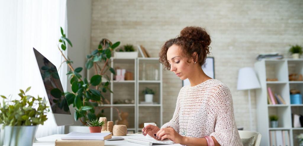 Woman sitting at desk typing on a keyboard looking at her computer